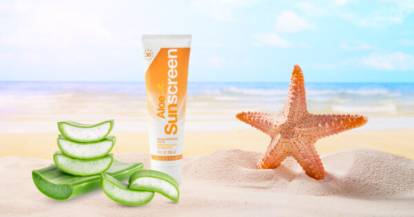 aloe sunscreen krema za sunčanje zapodena u pesak dok se pored nje nalazi morska zvezda i presečeni listovi aloje